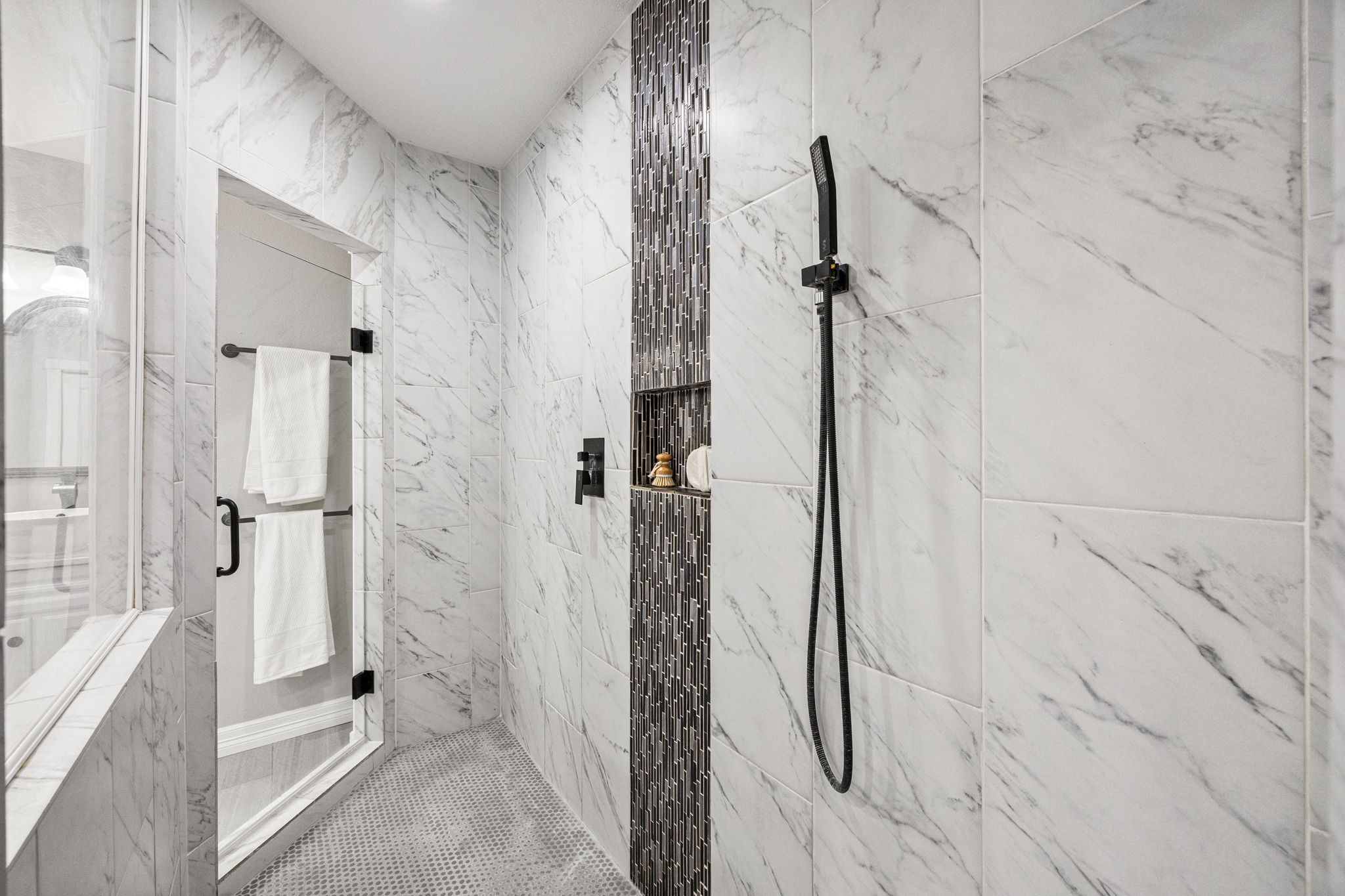1405 Walton Street Houston, TX 77009 - Photo 18 of 28 Luxurious walk-in shower with floor-to-ceiling marble-look tile, frameless glass enclosure, rainfall showerhead, and designer accent tile niche.