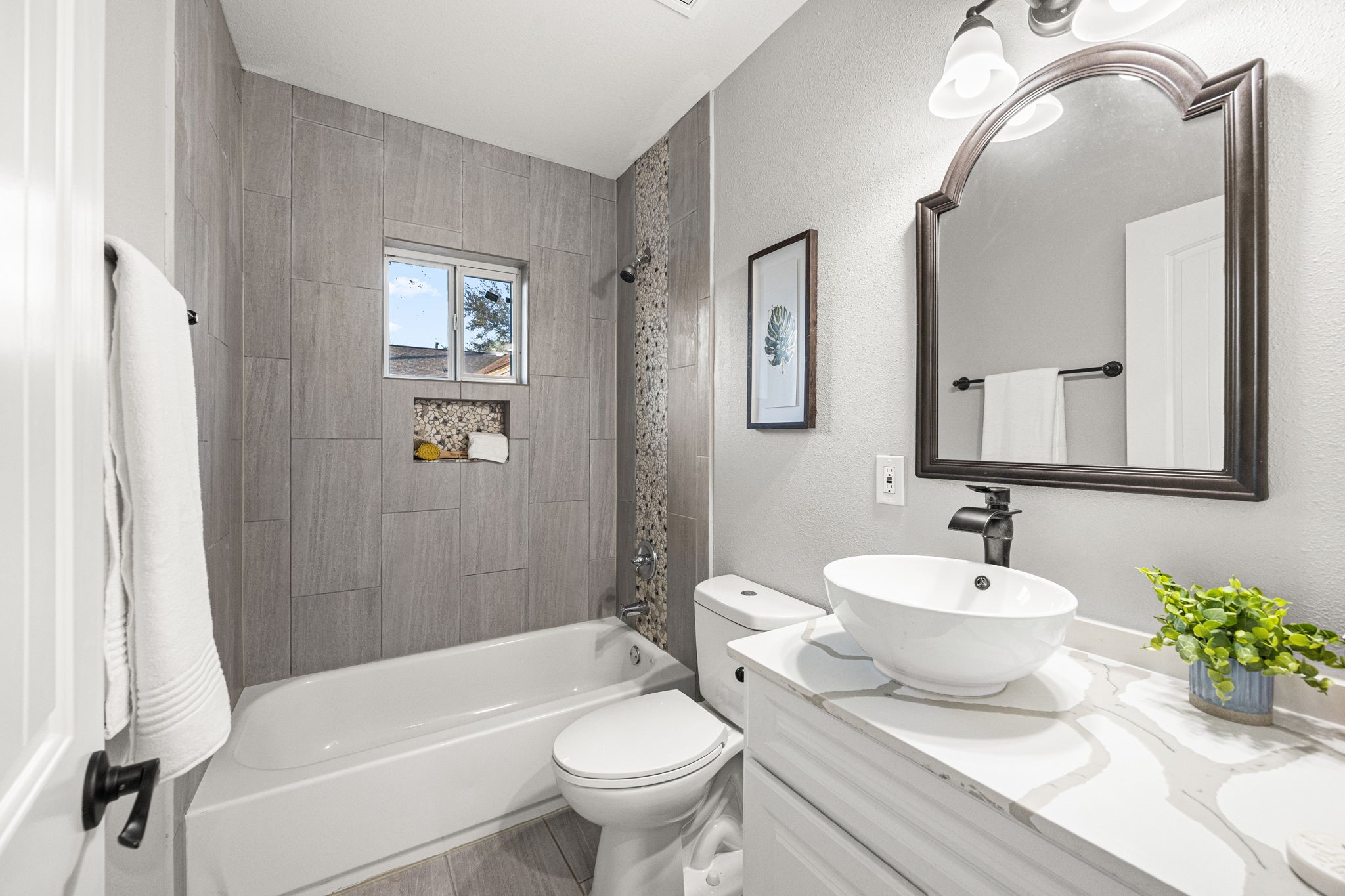 1405 Walton Street Houston, TX 77009 - Photo 21 of 28 Stylish secondary bath with tiled shower surround, niche detail, vessel sink, quartz countertop, and updated matte black fixtures.
