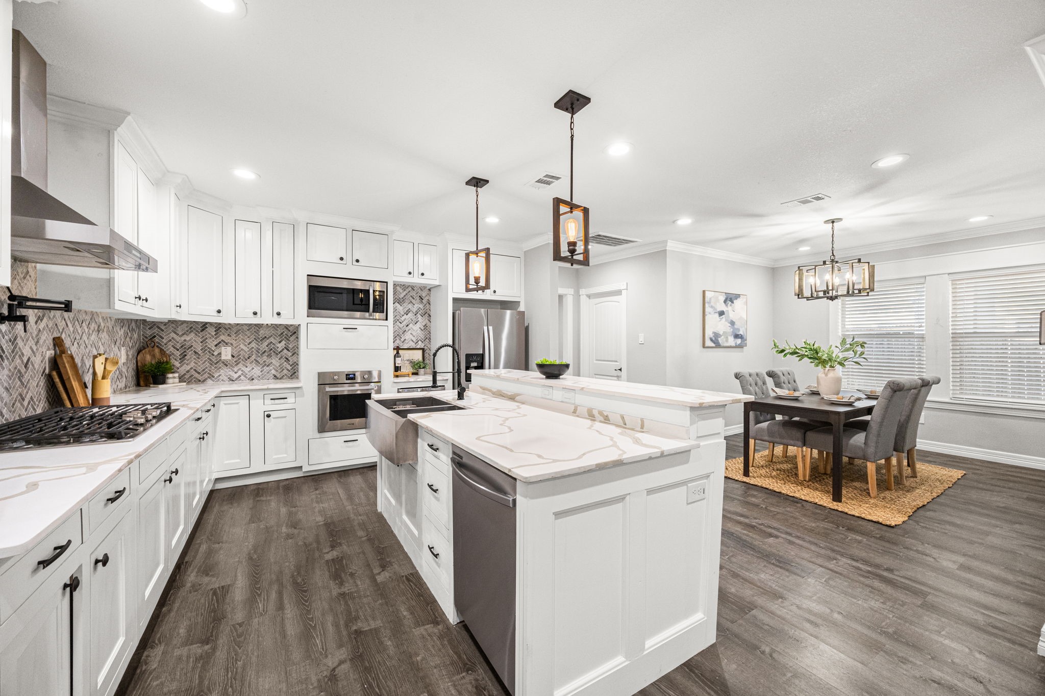 1405 Walton Street Houston, TX 77009 - Photo 6 of 28 Chef-inspired kitchen featuring expansive quartz countertops, apron-front sink, custom cabinetry with abundant storage, built-in microwave and oven, wine fridge, gas range with sleek vent hood, and striking herringbone backsplash. The open layout connects beautifully to the dining space, ideal for gatherings both large and intimate.