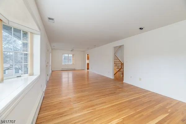 a view of an empty room with a window and wooden floor