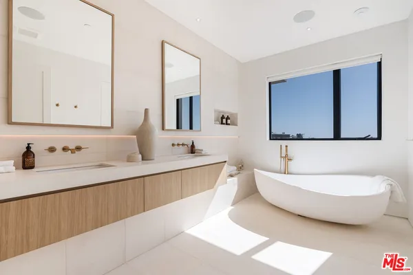 a spacious bathroom with a double vanity sink mirror and bathtub