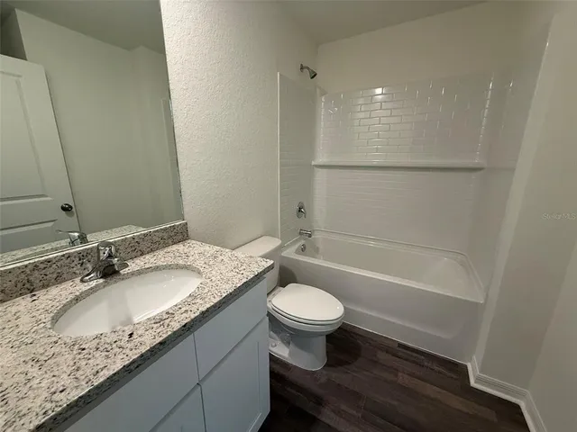 a bathroom with a granite countertop sink a toilet and bathtub