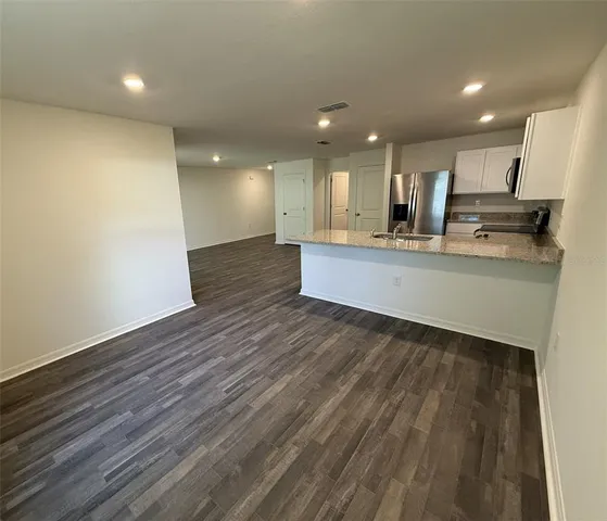 a large kitchen with stainless steel appliances a large counter top and wooden floors