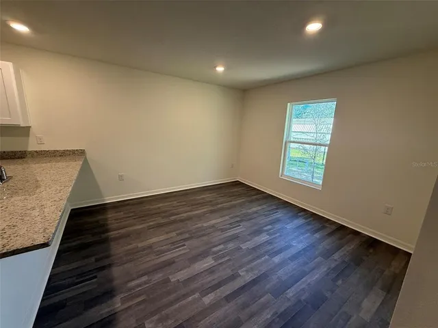 an empty room with wooden floor and a sink
