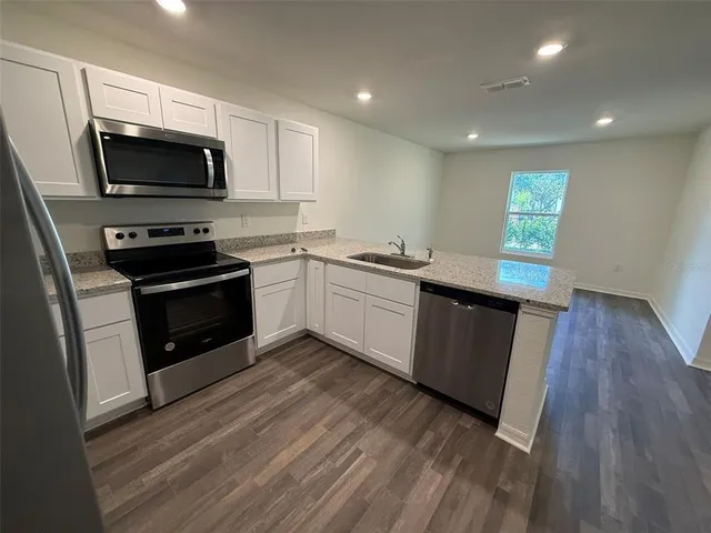 a kitchen with stainless steel appliances kitchen island granite countertop a stove a sink and a microwave