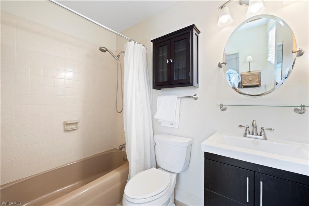 578 Broad Avenue South, Unit 578 Naples, FL 34102 - Photo 19 of 32 a bathroom with a toilet a sink a tub and mirror