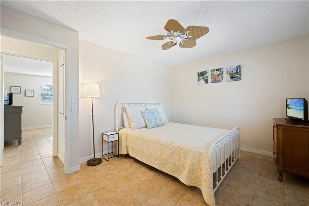 578 Broad Avenue South, Unit 578 Naples, FL 34102 - Photo 20 of 32 a bedroom with a bed and a chandelier