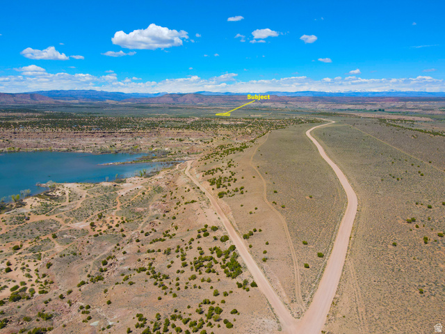 4500 South 22750th Duchesne, UT 84021 - Photo 4 of 34 Expansive desert landscape featuring a lake, winding unpaved roads, and distant mountains under a blue sky