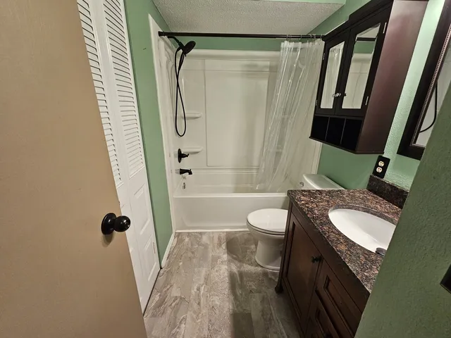 a bathroom with a granite countertop sink toilet and shower