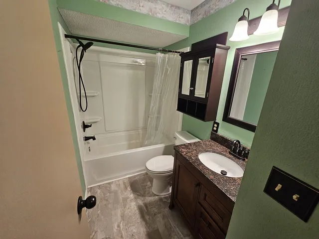 a bathroom with a granite countertop sink toilet and shower