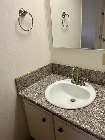 a bathroom with a granite countertop sink and a mirror