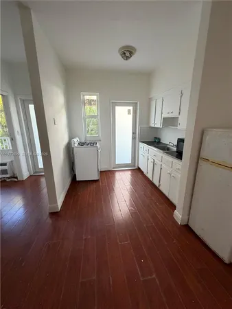 a kitchen with wooden floors and white cabinets
