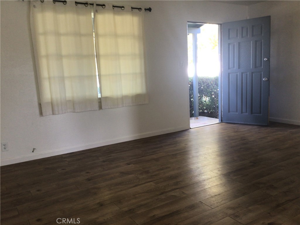 1202 West Lumber Street Lancaster, CA 93534 - Photo 4 of 16 an empty room with wooden floor and windows with curtains