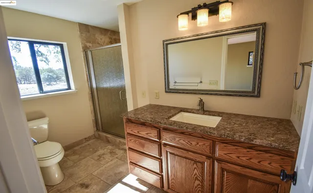 a bathroom with a granite countertop toilet sink and mirror