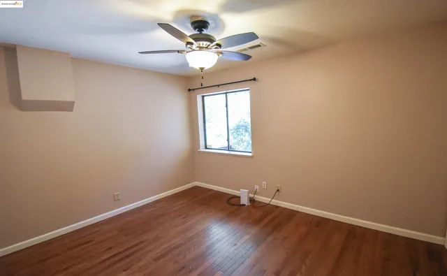 a view of a room with wooden floor and a ceiling fan