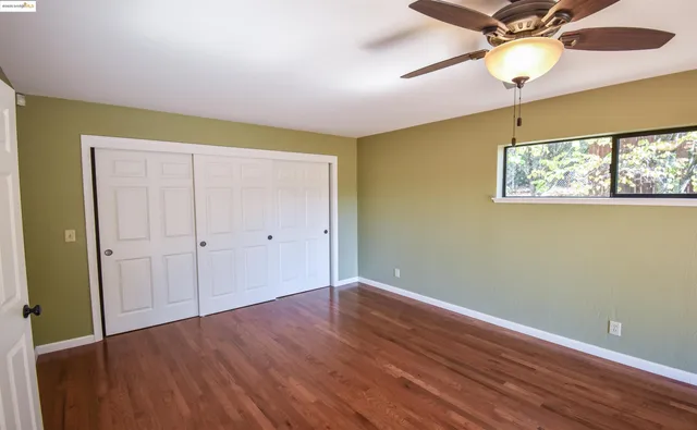 a view of an empty room with window and wooden floor
