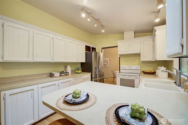 a kitchen with stainless steel appliances a white refrigerator a sink a stove and white cabinets