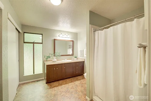 a view of bathroom with granite countertop shower sink and mirror