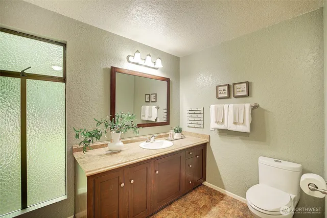 a spacious bathroom with a granite countertop sink toilet and mirror