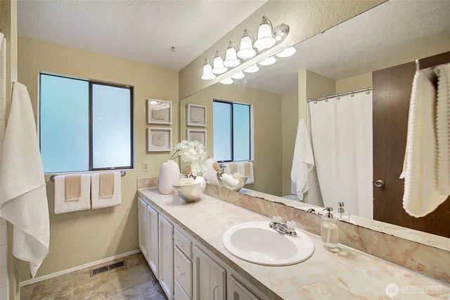 a bathroom with a granite countertop double vanity sink and mirror