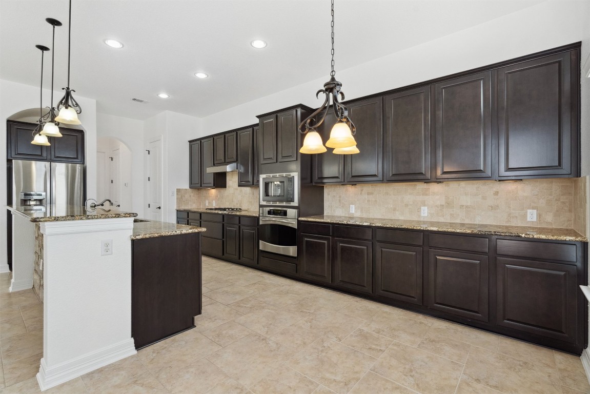 111 ANTONIO Way, Unit 5A Austin, TX 78734 - Photo 19 of 40 a kitchen with kitchen island granite countertop wooden cabinets and a refrigerator