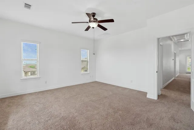 a view of an empty room with a window and a kitchen