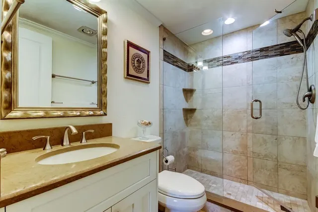 a bathroom with a granite countertop sink toilet a mirror a vanity and shower