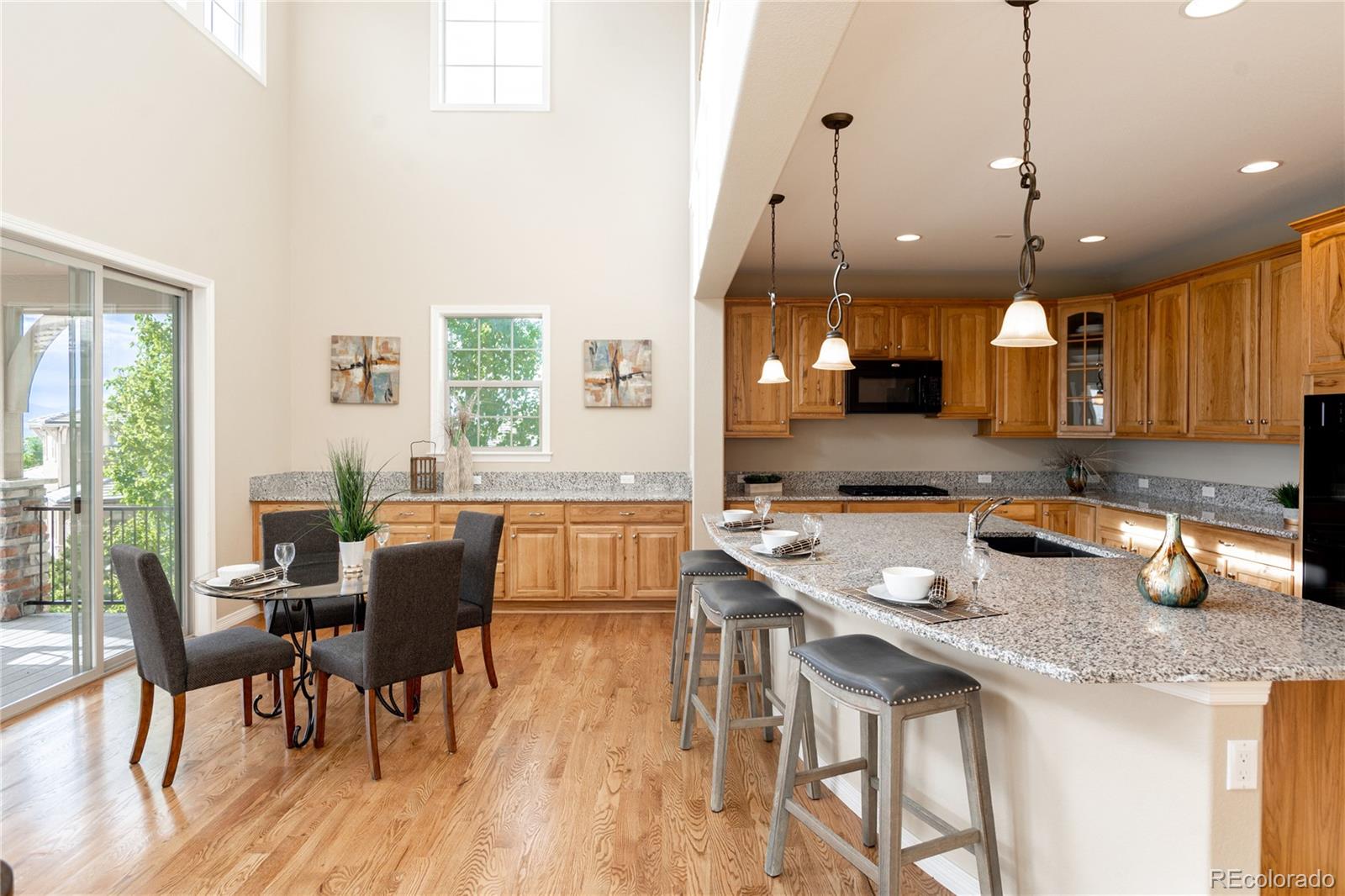 10599 Sundial Rim Road Highlands Ranch, CO 80126 - Photo 7 of 40 a kitchen with a table chairs sink and wooden floor