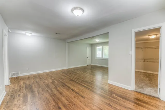 an empty room with wooden floor and windows