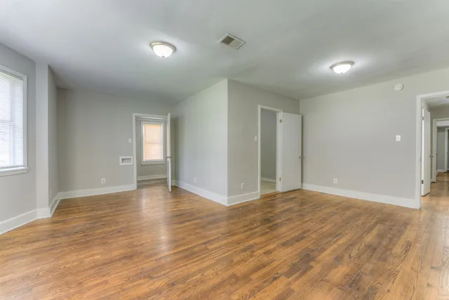 a view of an empty room with window and wooden floor