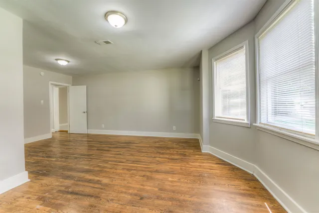 a view of an empty room with wooden floor and a window