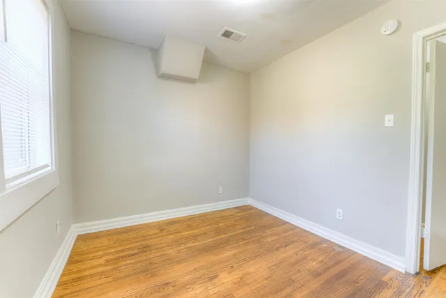 a view of empty room with wooden floor