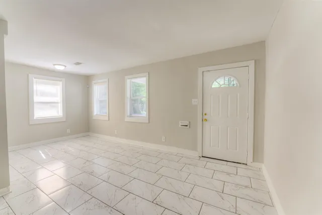 a view of an empty room with window and chandelier fan