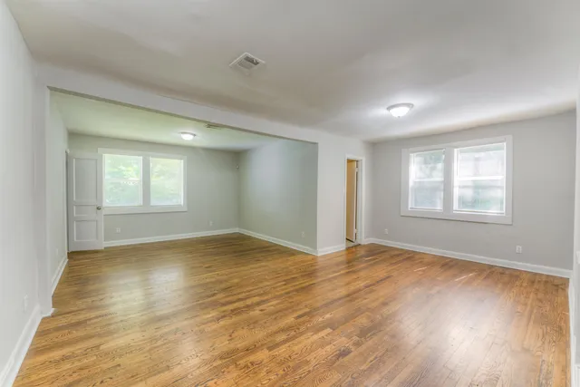 a view of an empty room with wooden floor and window