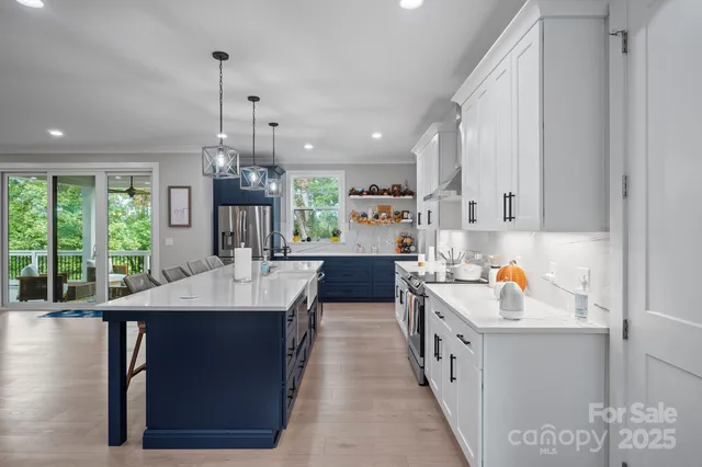 a kitchen with a stove a sink a refrigerator and a view of living room