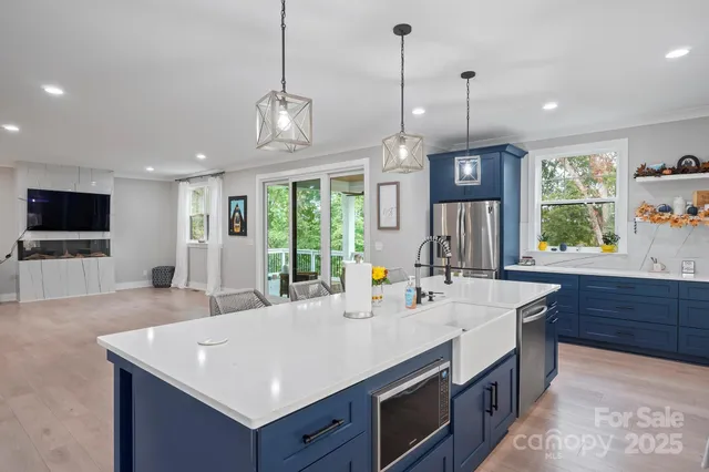 a kitchen with a stove a sink a center island and living room view