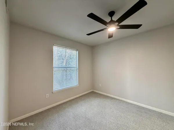 an empty room with ceiling fan and windows