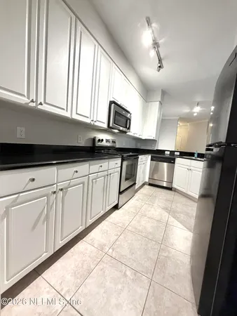 a kitchen with granite countertop a sink a counter top space appliances and cabinets