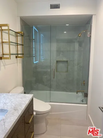 a bathroom with a granite countertop sink a toilet and shower