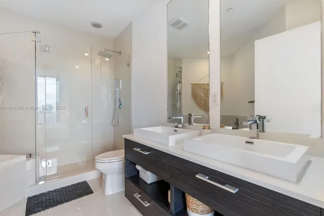 a bathroom with a double vanity sink toilet and shower