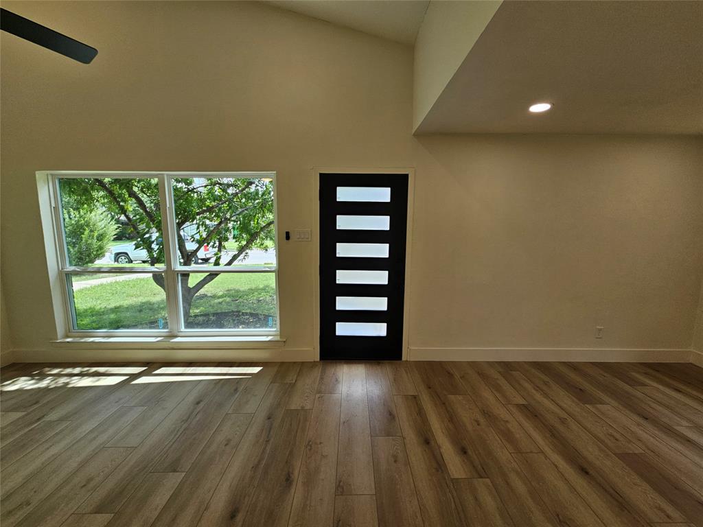 1725 R Avenue, Unit 1725 Plano, TX 75074 - Photo 2 of 20 Spacious living area featuring high vaulted ceilings, wood-finish flooring, a contemporary entry door with frosted glass inserts, recessed lighting, and a large picture window