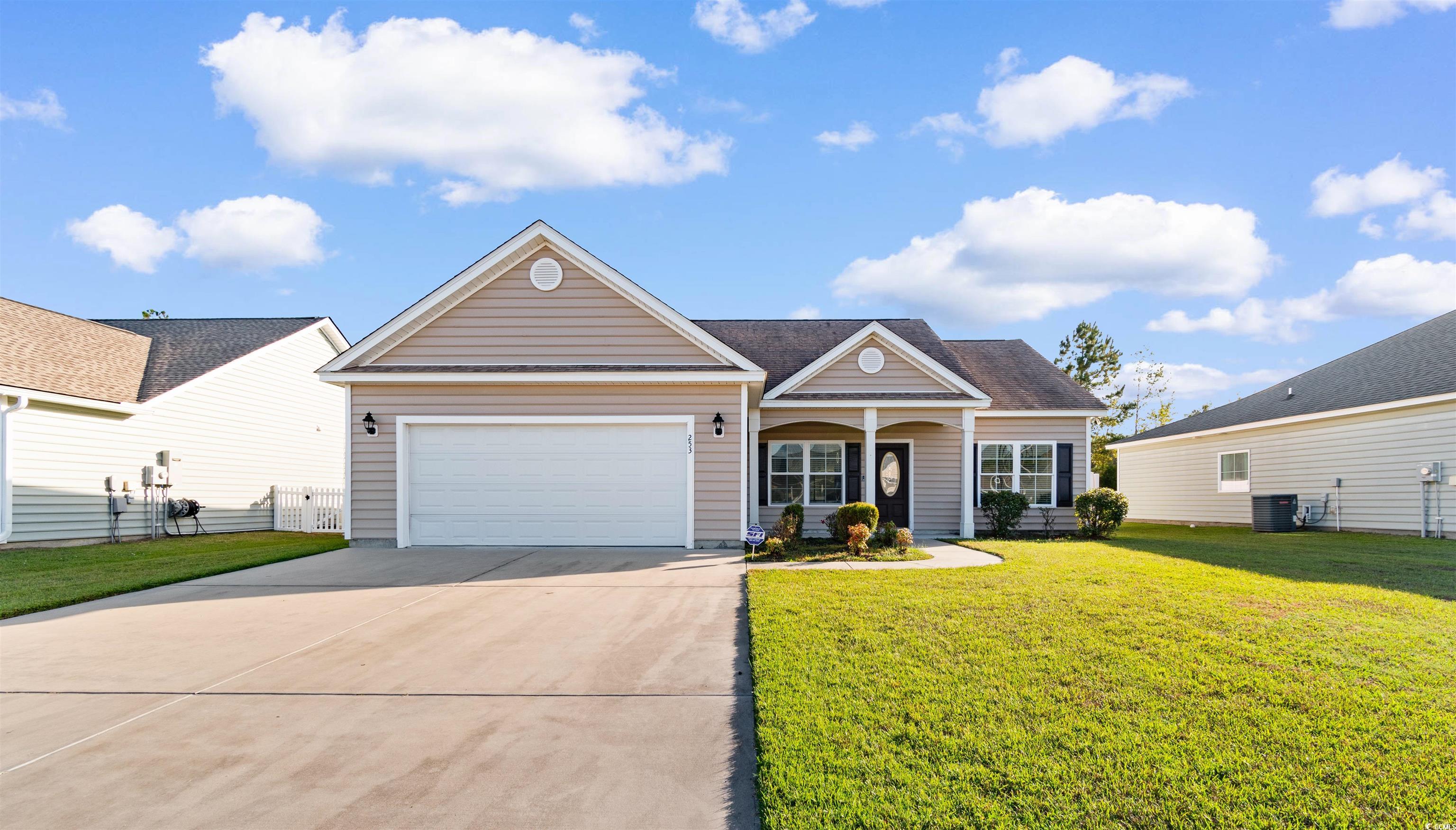 View of front of property featuring driveway, a front lawn, an attached garage, and covered porch