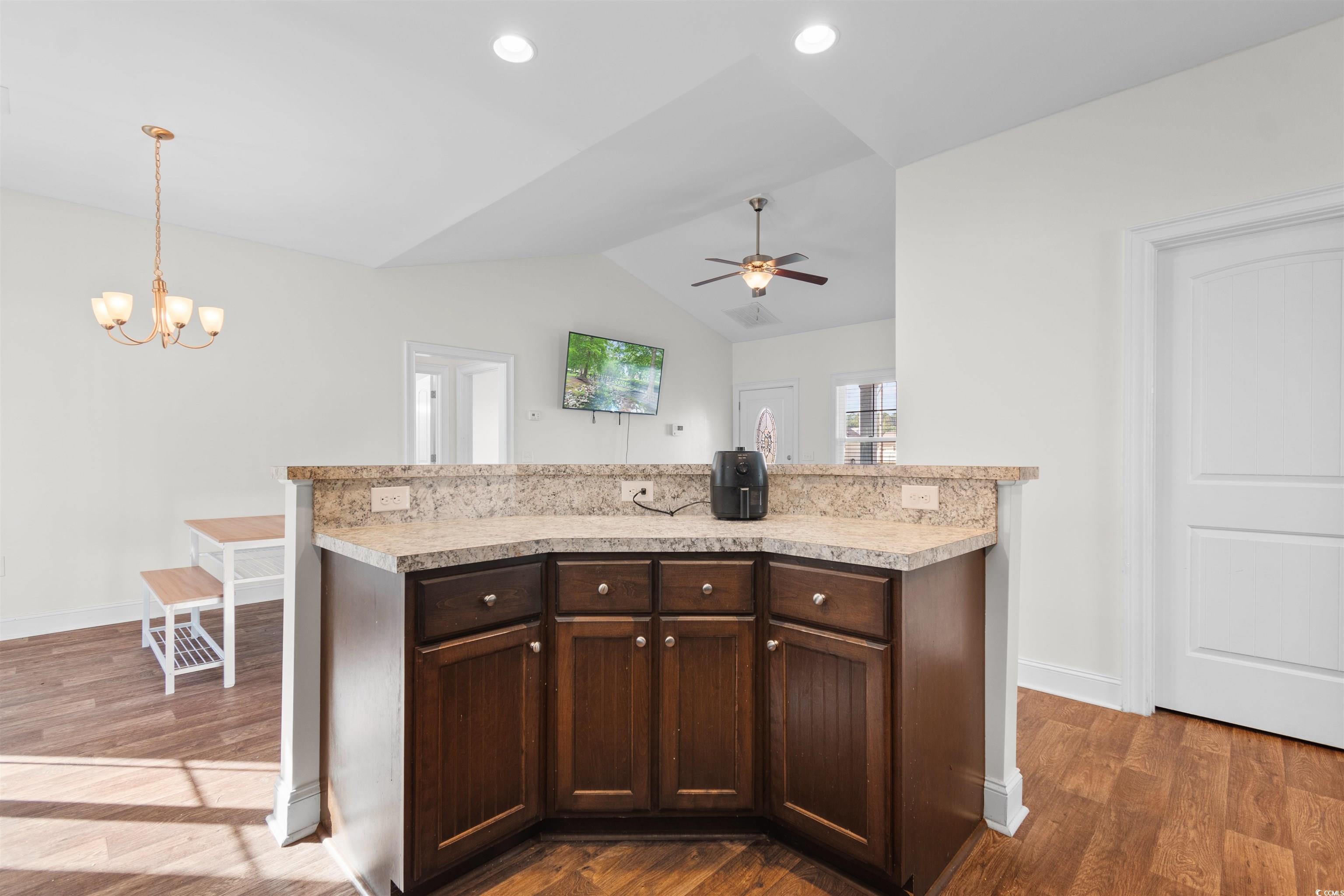 253 Maple Oak Drive Conway, SC 29526 - Photo 12 of 33 Kitchen featuring dark brown cabinets, light countertops, vaulted ceiling, a center island, and dark wood-style floors