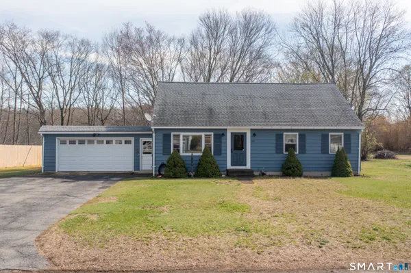 a front view of house with yard and trees in the background