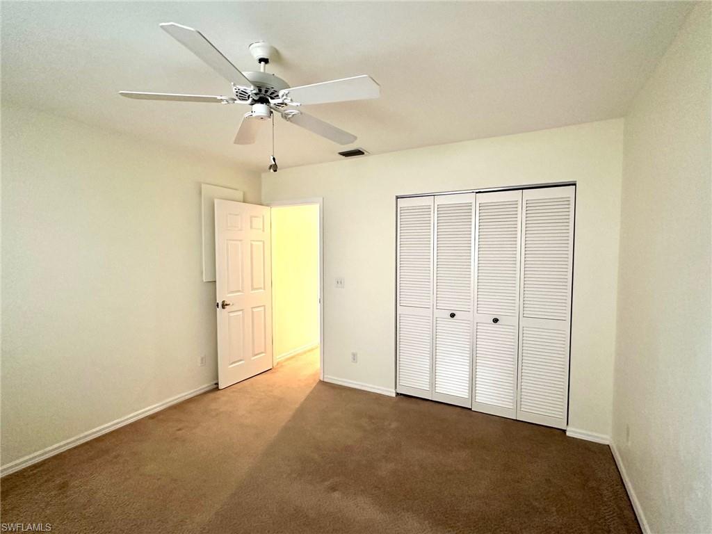 2525 Sailors Way, Unit 139 Naples, FL 34109 - Photo 11 of 20 Unfurnished bedroom featuring ceiling fan, dark carpet, and a closet