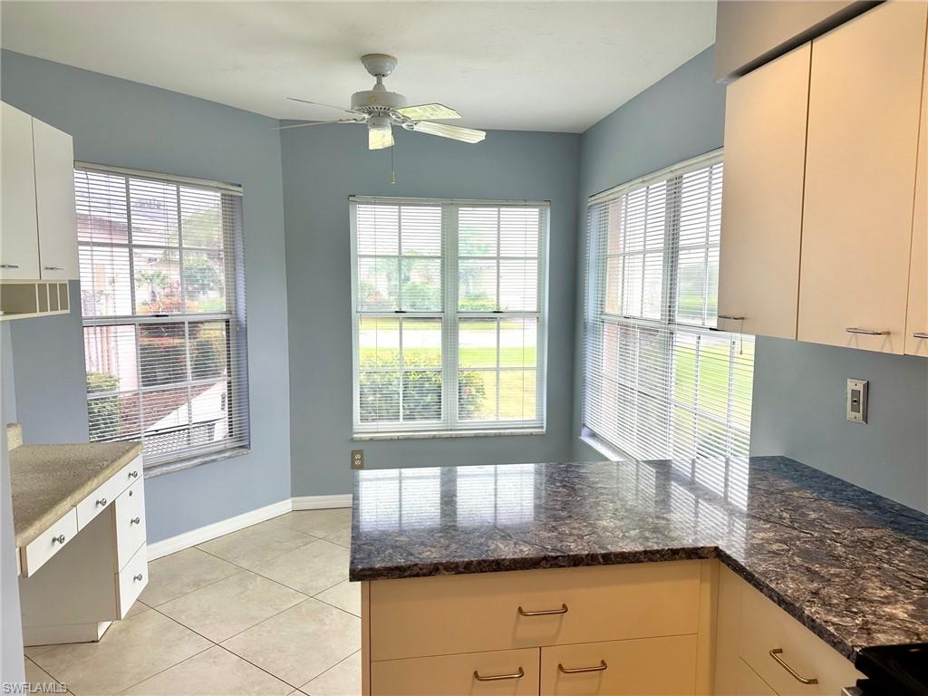 2525 Sailors Way, Unit 139 Naples, FL 34109 - Photo 4 of 20 Kitchen with light tile patterned flooring, white cabinetry, ceiling fan, and dark stone countertops