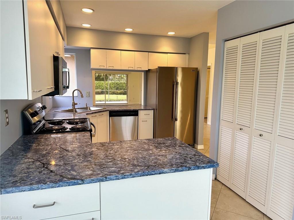 2525 Sailors Way, Unit 139 Naples, FL 34109 - Photo 5 of 20 Kitchen featuring kitchen peninsula, appliances with stainless steel finishes, sink, white cabinets, and light tile patterned flooring