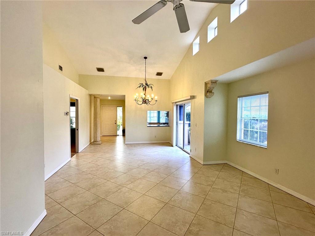 2525 Sailors Way, Unit 139 Naples, FL 34109 - Photo 8 of 20 Tiled empty room featuring ceiling fan with notable chandelier, a wealth of natural light, and a high ceiling