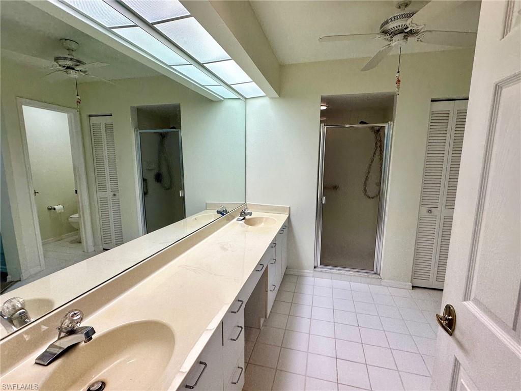 2525 Sailors Way, Unit 139 Naples, FL 34109 - Photo 10 of 20 Bathroom featuring toilet, a skylight, vanity, ceiling fan, and a shower with door