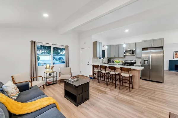 a living room with furniture kitchen and a wooden floor